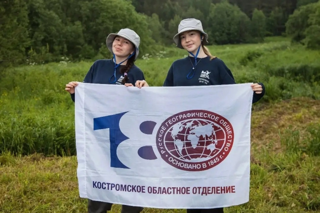 Участницы экспедиции с флагом Костромского областного отделения РГО на фоне природного ландшафта