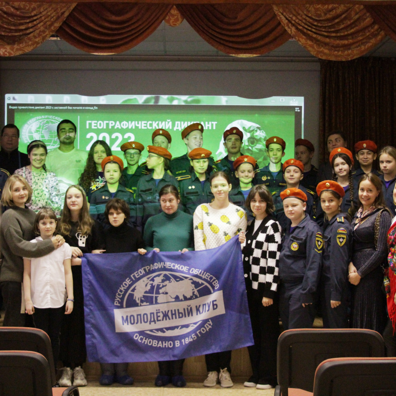 Участники Географического диктанта-2023 в актовом зале школы №340 Санкт-Петербурга с флагом МК РГО