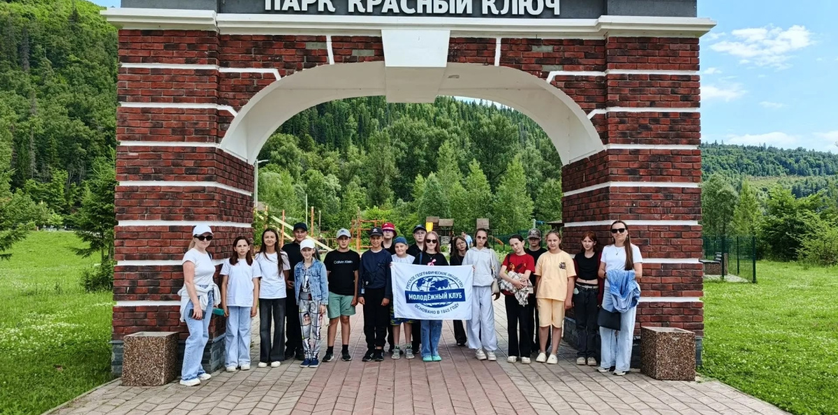Группа активистов с флагом молодёжного клуба у арки парка «Красный Ключ»