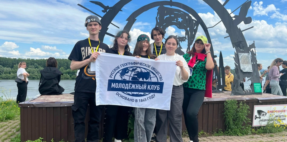  Активисты МК РГО «Север» с флагом клуба на фоне монументальной композиции у реки Белой