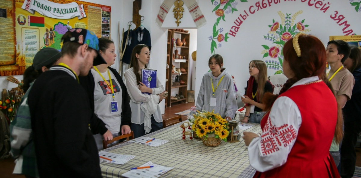 Экскурсовод в национальном костюме рассказывает участникам о белорусских традициях Экскурсовод в национальном костюме рассказывает участникам о белорусских традициях