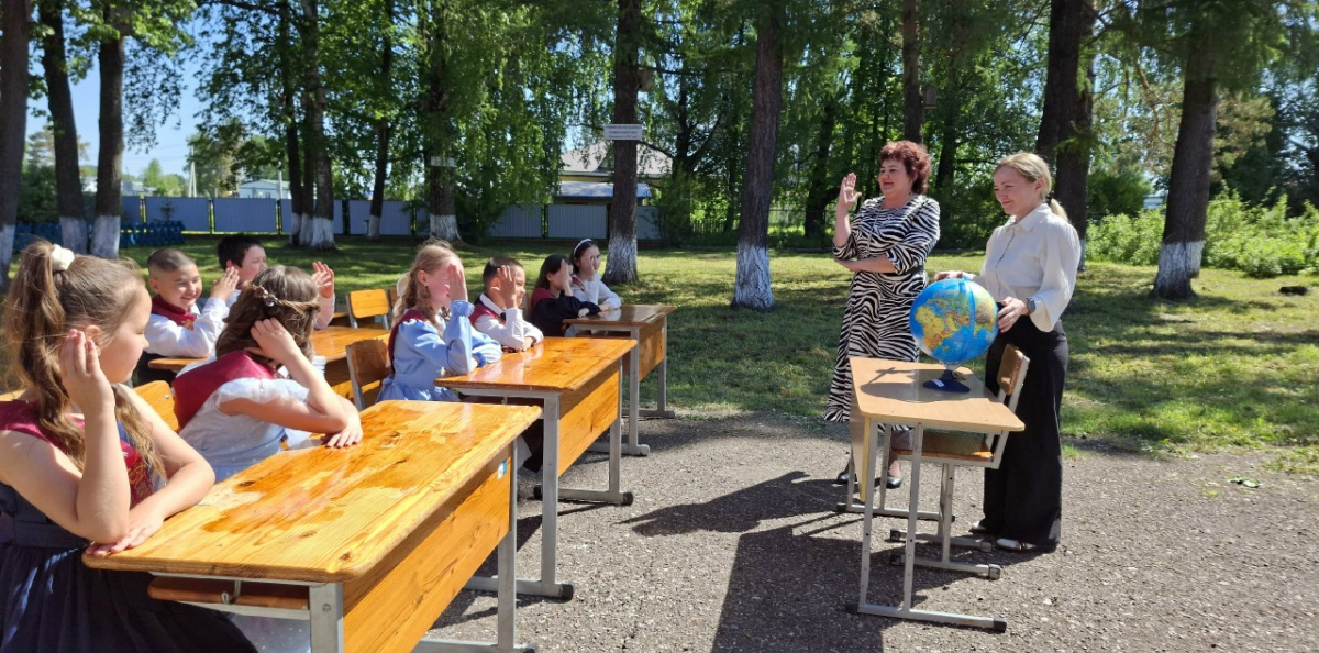 Школьники внимательно слушают объяснения руководителя клуба о свойствах глобуса