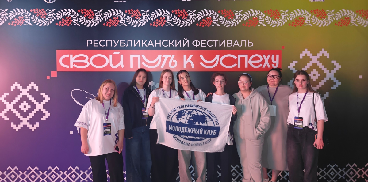 Команда Молодёжного клуба РГО "Компас мечты" Республики Башкортостан на фоне баннера Республиканского фестиваля «СВОй путь к успеху»