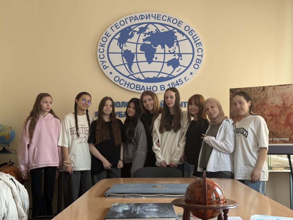 Участники мероприятия на фоне логотипа Русского географического общества в Молодёжном центре РГО Республики Башкортостан