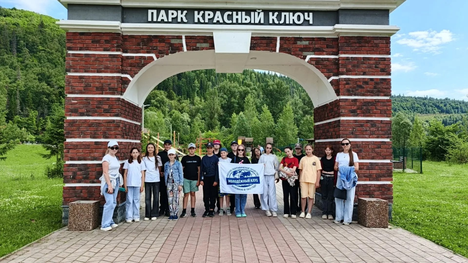 Группа активистов с флагом молодёжного клуба у арки парка «Красный Ключ»