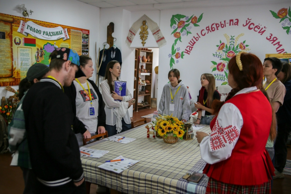 Экскурсовод в национальном костюме рассказывает участникам о белорусских традициях