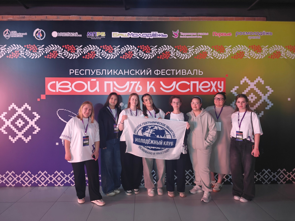 Команда Молодёжного клуба РГО "Компас мечты" Республики Башкортостан на фоне баннера Республиканского фестиваля «СВОй путь к успеху»